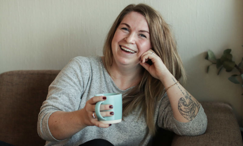 Bilde av Silje Ubostad. Hun sitter i en sofa med en kaffekopp i hånden.