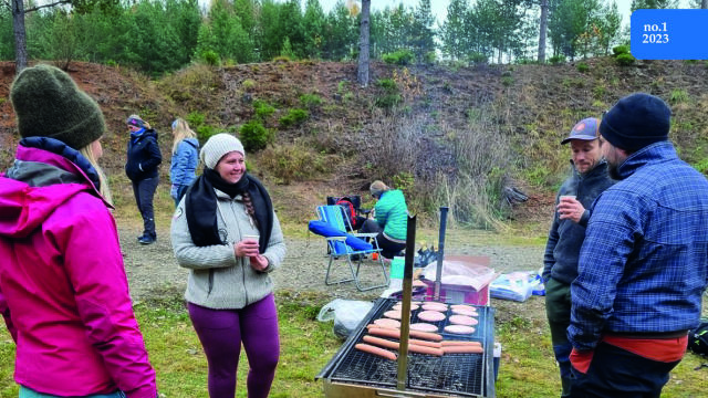 Personer som står rundt grill og griller pølser